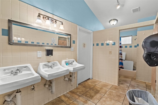 bathroom with tile walls, sink, tile patterned flooring, and vaulted ceiling