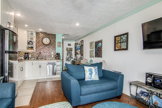 living room featuring crown molding, dark wood-type flooring, a textured ceiling, and indoor wet bar