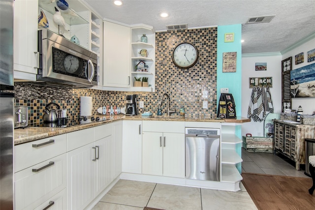 kitchen featuring light stone counters, appliances with stainless steel finishes, tasteful backsplash, and white cabinets