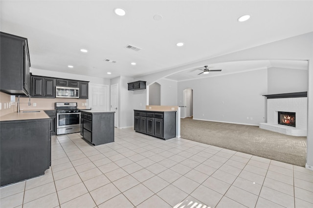 kitchen with a center island, light colored carpet, visible vents, appliances with stainless steel finishes, and dark cabinets