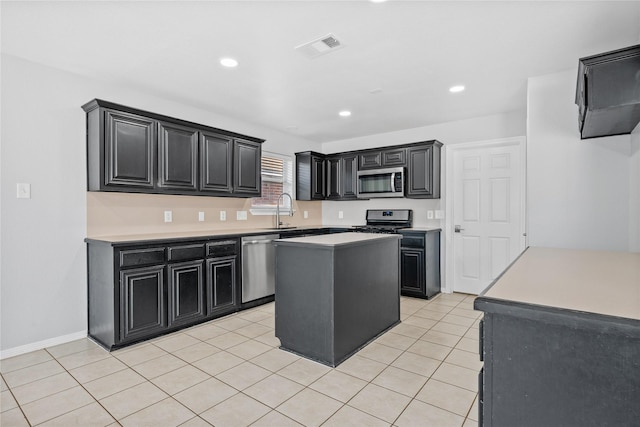 kitchen with light tile patterned floors, stainless steel appliances, a kitchen island, a sink, and dark cabinetry