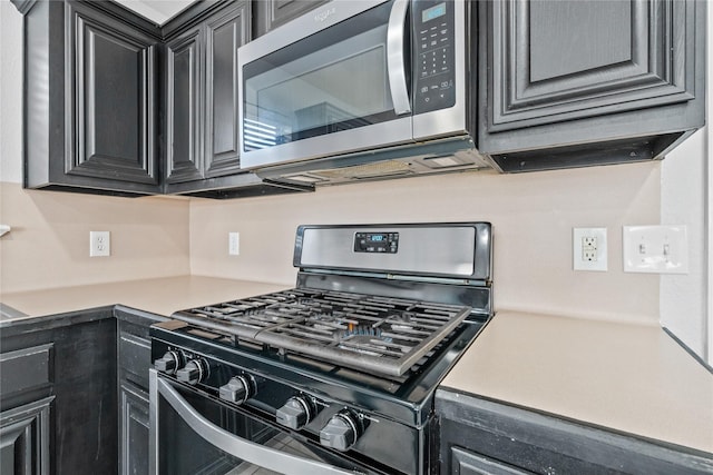 kitchen featuring appliances with stainless steel finishes, light countertops, and dark cabinets