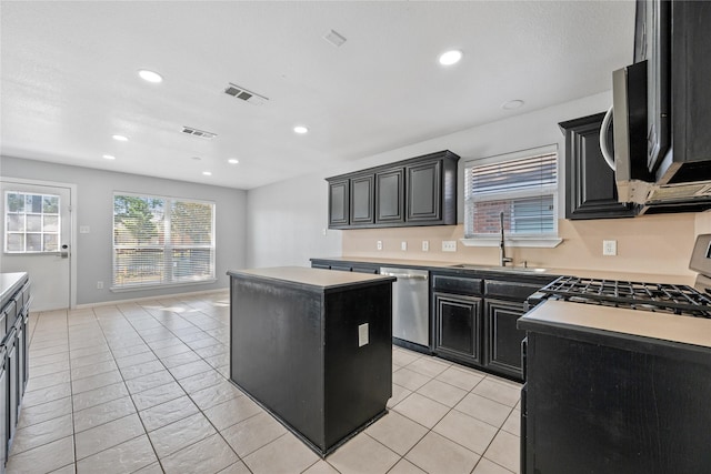 kitchen with visible vents, a kitchen island, dark cabinets, stainless steel appliances, and a sink