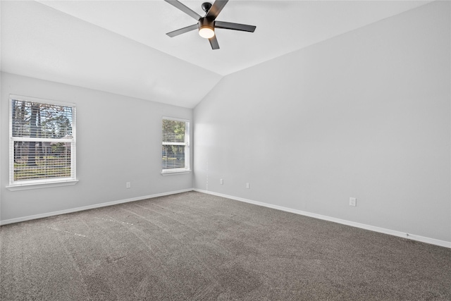 empty room with a ceiling fan, carpet flooring, vaulted ceiling, and baseboards