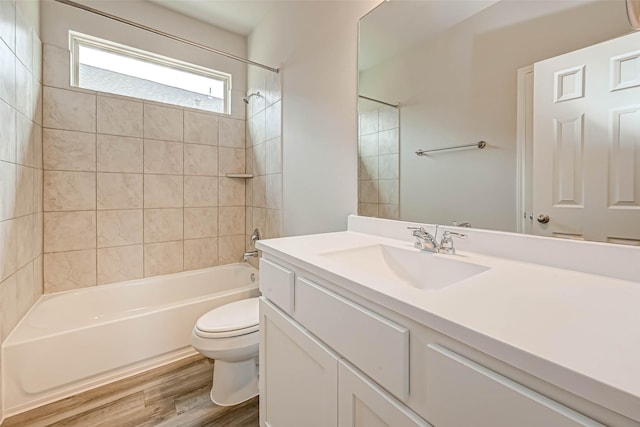 full bathroom with hardwood / wood-style flooring, tiled shower / bath, vanity, and toilet