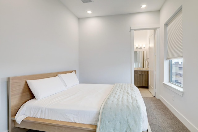 bedroom featuring ensuite bath and light colored carpet