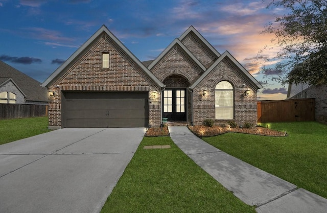 french country inspired facade featuring a garage and a lawn