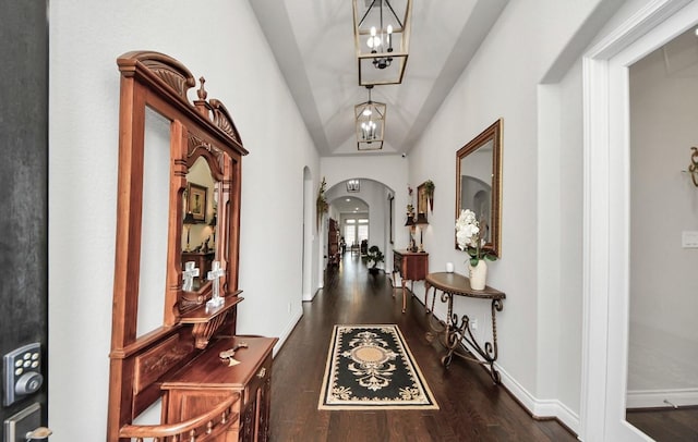 hallway with a notable chandelier, vaulted ceiling, and dark hardwood / wood-style floors