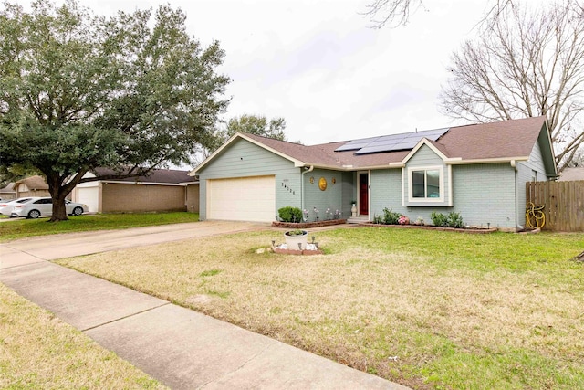 ranch-style house featuring a garage, a front yard, and solar panels