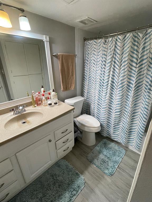 bathroom featuring vanity, wood-type flooring, curtained shower, and toilet