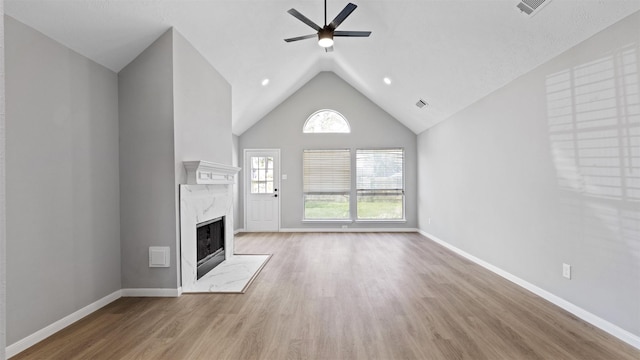 unfurnished living room with visible vents, a ceiling fan, a high end fireplace, wood finished floors, and baseboards