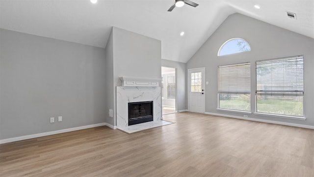 unfurnished living room with visible vents, a high end fireplace, ceiling fan, high vaulted ceiling, and light wood-type flooring