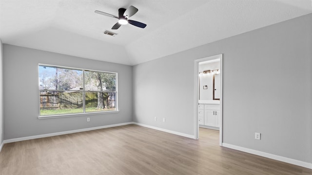 unfurnished bedroom with baseboards, visible vents, connected bathroom, lofted ceiling, and wood finished floors