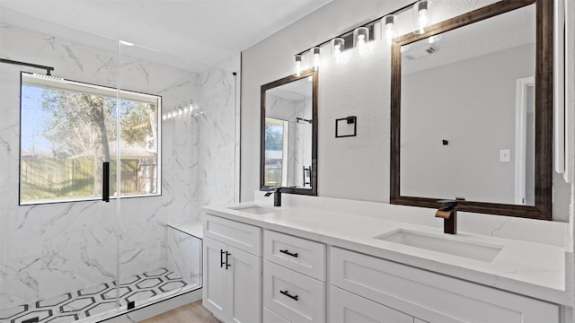 bathroom featuring visible vents, a sink, a marble finish shower, and double vanity