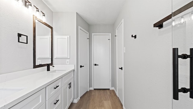 bathroom featuring double vanity, baseboards, a sink, and wood finished floors