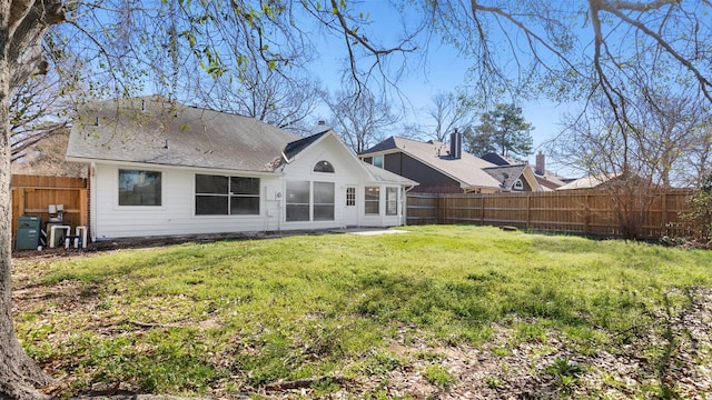 rear view of property with a fenced backyard and a lawn