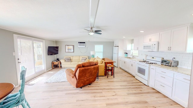 29331 County Rd 25, Damon, TX 77430 - kitchen featuring vaulted ceiling, sink, white cabinets, light stone countertops, and white appliances