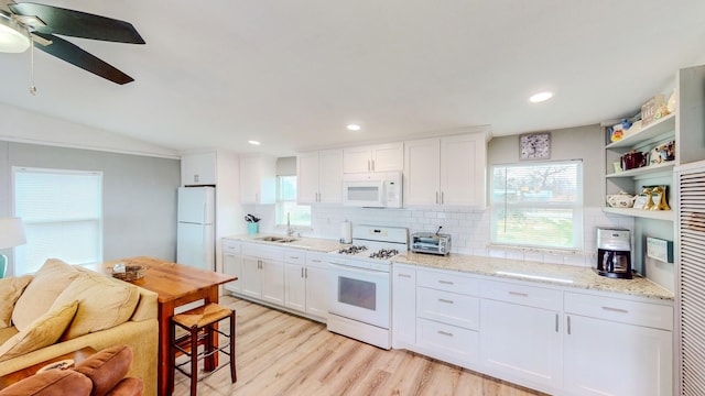 29331 County Rd 25, Damon, TX 77430 - kitchen featuring white cabinetry, decorative backsplash, light stone counters, light hardwood / wood-style floors, and white appliances