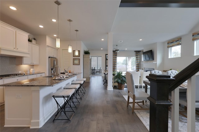 kitchen featuring stainless steel appliances, white cabinetry, a kitchen island with sink, and a kitchen bar