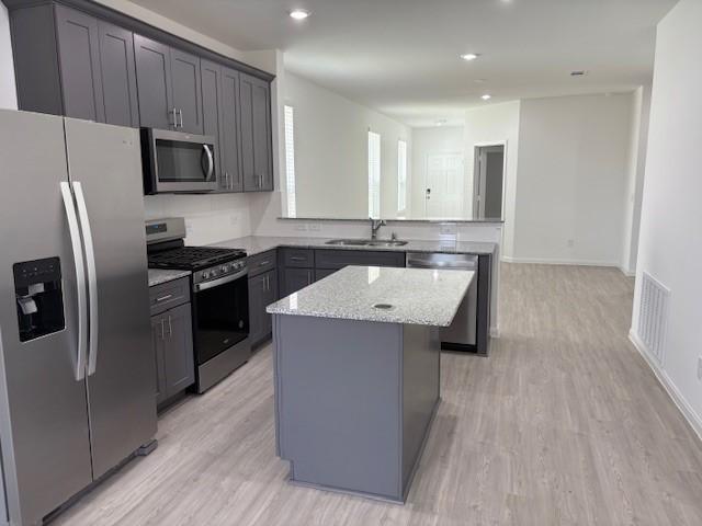 23506 Daisy Grubber Ln, Hockley, TX 77447 - kitchen featuring appliances with stainless steel finishes, a sink, a center island, light stone counters, and a peninsula