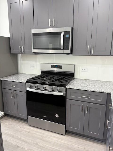 23506 Daisy Grubber Ln, Hockley, TX 77447 - kitchen with appliances with stainless steel finishes, light wood-type flooring, gray cabinets, and light stone counters