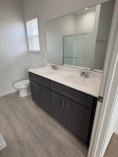 23506 Daisy Grubber Ln, Hockley, TX 77447 - bathroom featuring double vanity, a stall shower, toilet, baseboards, and wood finished floors