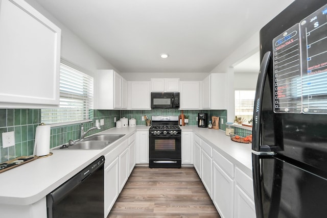 kitchen with white cabinetry, sink, black appliances, and decorative backsplash