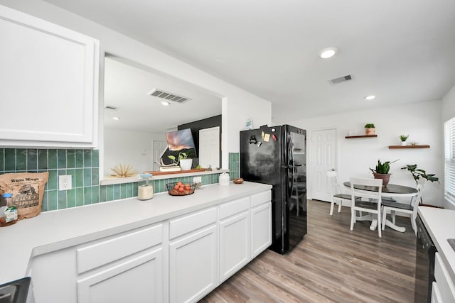 kitchen with white cabinets, light hardwood / wood-style floors, black appliances, and backsplash