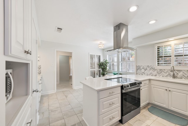 kitchen with sink, appliances with stainless steel finishes, white cabinetry, island range hood, and kitchen peninsula