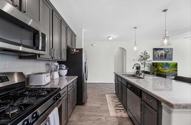 kitchen featuring sink, hardwood / wood-style flooring, appliances with stainless steel finishes, a kitchen island with sink, and tasteful backsplash