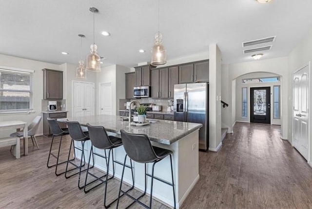 kitchen featuring a kitchen island with sink, decorative light fixtures, a breakfast bar area, and stainless steel appliances