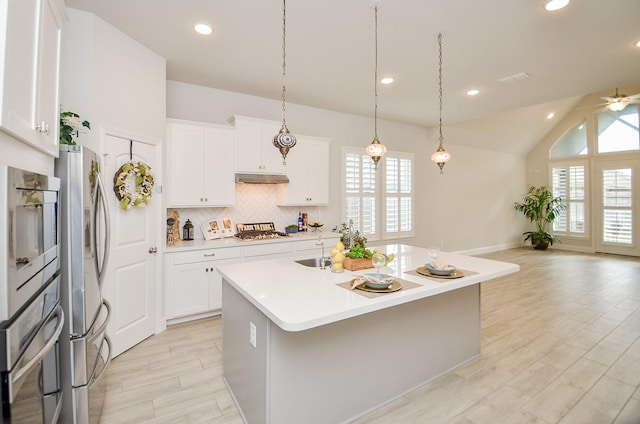 kitchen with stainless steel appliances, a kitchen island with sink, hanging light fixtures, and white cabinets