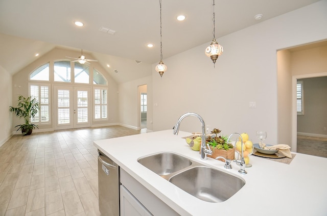 kitchen with lofted ceiling, sink, decorative light fixtures, stainless steel dishwasher, and white cabinets