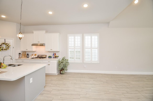 kitchen with pendant lighting, sink, white cabinets, decorative backsplash, and stainless steel gas stovetop