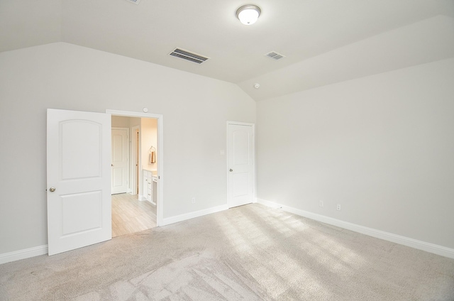 unfurnished bedroom with light colored carpet and lofted ceiling