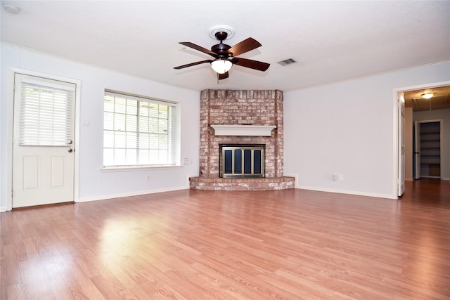 unfurnished living room featuring crown molding, ceiling fan, hardwood / wood-style floors, and a brick fireplace