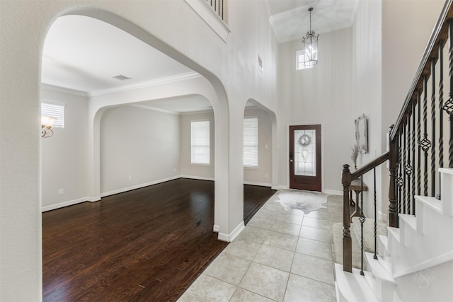 foyer entrance with crown molding, a healthy amount of sunlight, a chandelier, and light hardwood / wood-style floors