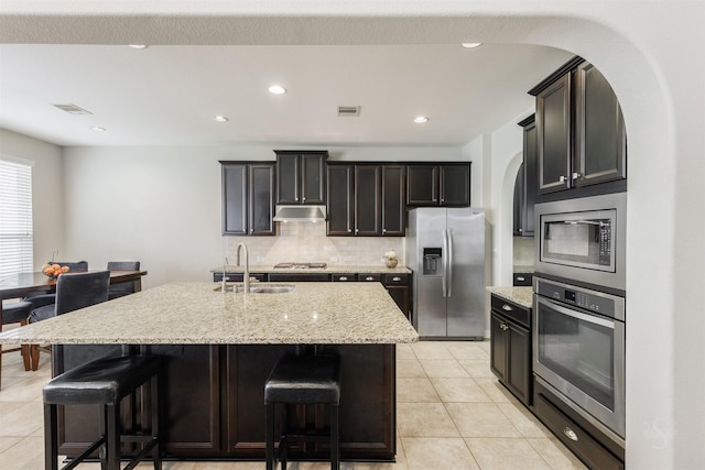 kitchen featuring appliances with stainless steel finishes, a kitchen breakfast bar, sink, and a center island with sink