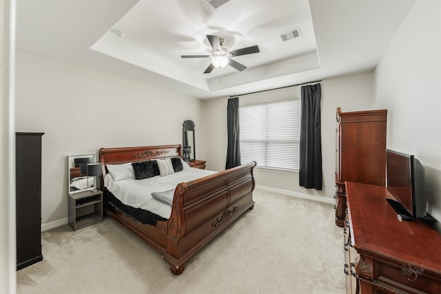 carpeted bedroom featuring ceiling fan and a tray ceiling