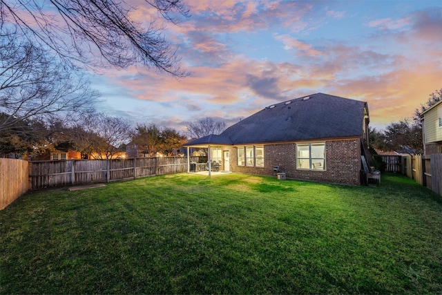 back house at dusk with a lawn and a patio