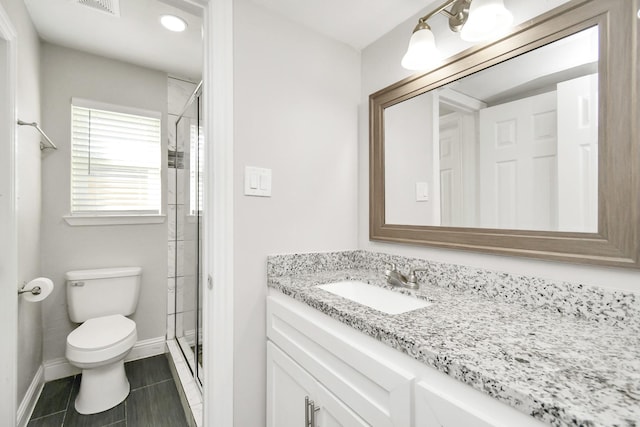 bathroom featuring a shower with door, vanity, tile patterned flooring, and toilet