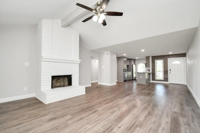 unfurnished living room featuring ceiling fan, wood-type flooring, a fireplace, and vaulted ceiling with beams