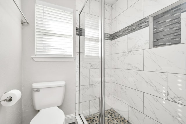 bathroom featuring a tile shower and toilet