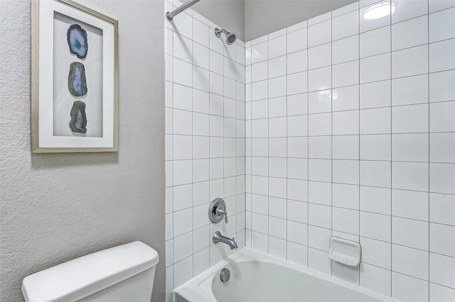 bathroom with tiled shower / bath combo and toilet