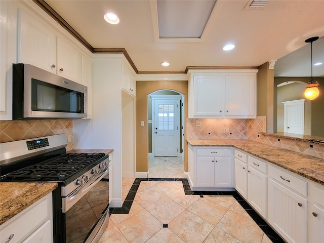 kitchen with light stone counters, crown molding, decorative light fixtures, appliances with stainless steel finishes, and white cabinets