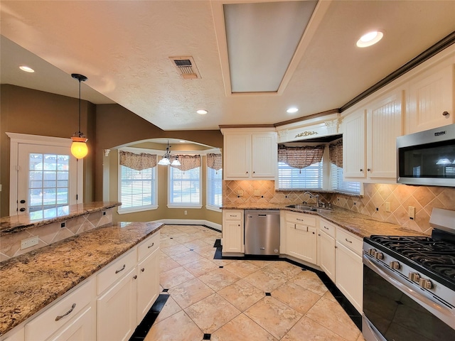 kitchen with white cabinetry, light stone counters, pendant lighting, stainless steel appliances, and backsplash