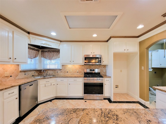 kitchen with sink, white cabinets, decorative backsplash, light stone counters, and stainless steel appliances