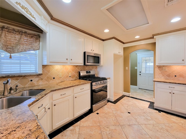 kitchen featuring stainless steel appliances, white cabinetry, light stone countertops, and sink