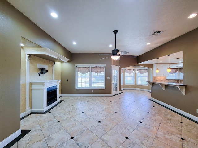 unfurnished living room featuring light tile patterned floors and ceiling fan