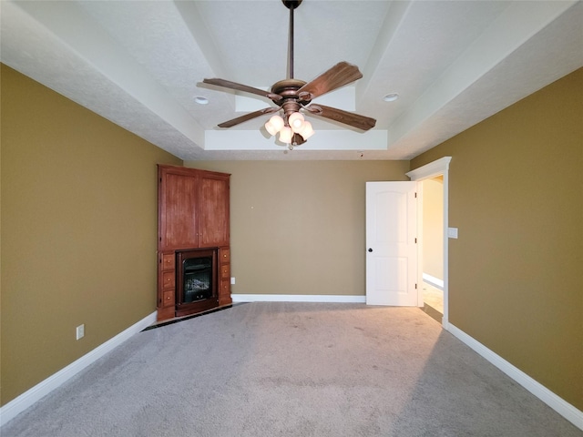 unfurnished living room featuring light carpet, ceiling fan, and a tray ceiling